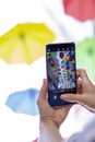 Vertical photo. Hand with smartphone in hand takes off colorful umbrellas over pedestrian street