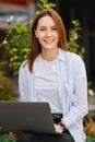 Vertical photo of happy casual young woman working on laptop remote outdoor Royalty Free Stock Photo