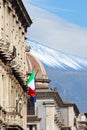 Vertical photo of historical building in Sicilian Catania, Italy with waving Italian flag on the facade. In background cupola of Royalty Free Stock Photo