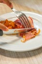 Vertical photo of human hand cutting bacon slice