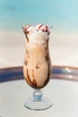 Vertical photo of icy coffee cocktail on the glass table at the beach with ocean