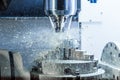 Vertical photo of industrial wet milling process in 5-axis cnc machine with coolant flow under pressure and freezed splashes