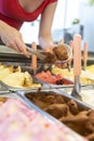 Ice cream showcase with a saleswoman preparing a chocolate flavored tub