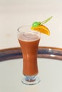 Vertical photo of Mrs. Robinson Seltzer cocktail with piece of orange on the glass table ocean background at the beach Royalty Free Stock Photo