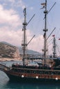 Vertical photo. Old pirate ship on the water of Mediteranean sea. Tourist entertainment, coastal tour. Summer sunny day. Mountain