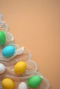 vertical photo with painted Easter eggs on lace against background of peach fluff with copy space.