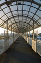 Vertical photo of a pedestrian bridge with railings and canopy in perspective in sunlight at sunset Royalty Free Stock Photo