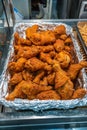 Vertical photo of pile of fried chicken drumsticks at market