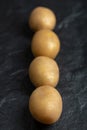 Vertical photo of pile of potatoes in a row on black background