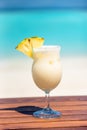 Vertical photo of Pina colada coktail with slice of pineapple on wooden table at the beach