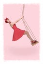 Vertical photo on a pink background of a naughty girl in a polka dot dress on a swing Royalty Free Stock Photo