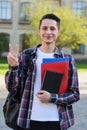 Vertical photo portrait of handsome attractive cute playful smart guy holding pile of notepads in hands giving v-sign to you