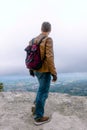 Vertical photo Portrait of a man dressed in a stylish brown leather jacket and jeans. backpack watches and biker gloves. posing on