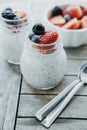 Vertical photo of Pudding with chia seeds, yogurt and fresh fruits: Strawberries, blueberries and blackberries in glass jars on w Royalty Free Stock Photo