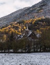 Vertical photo of a rural church covered with snow and surrounded by trees and mountains