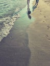 vertical photo, sea and sandy beach at sunset, footprints in sand, two pairs of feet walking along beach. beach holiday Royalty Free Stock Photo