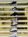 A Vertical photo of 7 shelves of New Nike Shoes against a Gold Colored Mirror