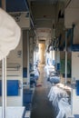 Vertical photo - sleeping reserved seat wagon for long-distance travel, view of the passage. Blue