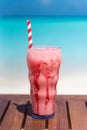 Vertical photo of Strawberry Frappuccino drink with straw on wooden table ocean background at the beach