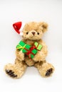 Vertical photo with stuffed toy Teddy bear in a red Santa Claus hat with a pompom on one ear, holding green gift boxes in its paws Royalty Free Stock Photo