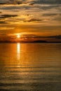 Vertical photo of Sunset over Umea river Mountains, summer sky with clouds highlighted by orange red Sun. Sunlight path on water Royalty Free Stock Photo