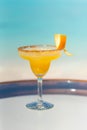 Vertical photo tasty fresh icy yellow color cocktail on the glass table at the beach with ocean Royalty Free Stock Photo