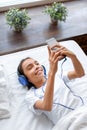 Vertical photo of a teenage girl in bed with a smartphone during an online video call. She communicates with her friends