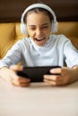 Vertical photo of a teenage girl playing an online game on her smartphone. She screams emotionally in an attempt to win