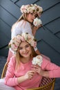 Vertical photo of two cheerful young girls in wreaths of roses