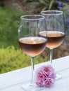 A vertical photo of two glasses of rosÃÂ© wine outside