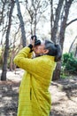 Vertical photo of the a Woman makes photos with analog reflex camera in the forest