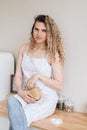 Vertical photo of a woman sitting on a kitchen table with a jar of pasta in her hands. scandinavian interior Royalty Free Stock Photo