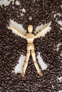 Vertical photo of wooden mannequin figure doing a snow angle in a pile of coffee beans