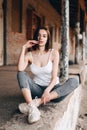 A vertical photo of a young girl, sitting on her bottom, her legs folded in front, along a brick old building Royalty Free Stock Photo