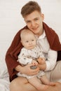 Vertical photo of young smiling man dad holding baby and toys, weekend activity. Tender and caring parenthood. Close up