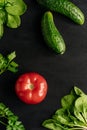 Vertical photograph fresh vegetables on dark background. Cucumbers, tomato and fresh herbs. Ingredients for fresh salad