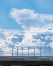 Vertical photograph of wind farm between crop fields. Blue sky with clouds Royalty Free Stock Photo