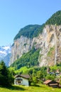 Vertical photography of picturesque village Lauterbrunnen in Swiss Alps. Famous Staubbach Falls in background. Tourists