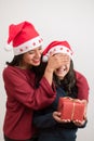 Vertical photography young mother covering eyes to surprise her daughter with a red present on white background