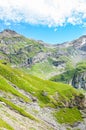 Vertical picture of amazing Alpine landscape photographed on a sunny day. Green pastures on rocky mountains. Beautiful Swiss