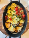 Vertical picture of an assortment of baked vegetables with provolone cheese melted on top.