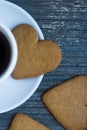 Vertical picture of gingerbread heart shaped biscuit on white porcelain plate. Coffee break with love. Side of coffee