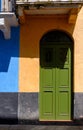 Vertical picture of a green door of a colorful building with a balcony under the sunlight at daytime