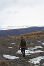 Vertical picture of a hiker with a camera on the hills covered in the snow in Iceland