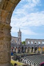 Vertical picture of the interior of Pula Arena, the only remaining Roman amphitheatre entirely preserved, with the tower of the