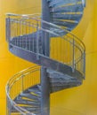 Vertical picture of a metallic spiral staircase under the lights against a yellow background Royalty Free Stock Photo