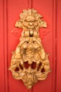 Vertical picture with old style decorated door knob in shape of satire head and two cupidons on red wooden door in Luberon, heart Royalty Free Stock Photo