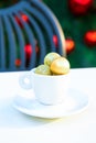 Vertical picture of porcelain coffee cup with golden Christmas balls inside. Coffee pair on white table angle, grey