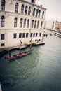 Vertical picture of a red gondola sailing on the grand channel next to the building in Venice, Italy