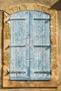 Vertical picture of typical traditional blue closed window shutters on stone yellow wall in Provence in sunny day. The facade of Royalty Free Stock Photo